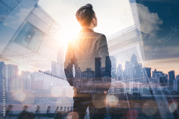 Fototapeta The double exposure image of the business man standing back during sunrise overlay with cityscape image. The concept of modern life, business, city life and internet of things.