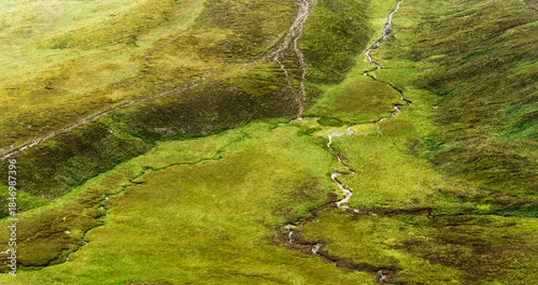 Fototapeta Streams and paths crisscross a green grassy landscape. The area is likely for hiking and is located within the Coomloughra Horseshoe region.