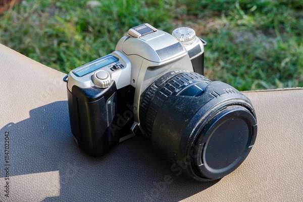 Obraz DSLR camera with zoom lens resting on cushion with grass background