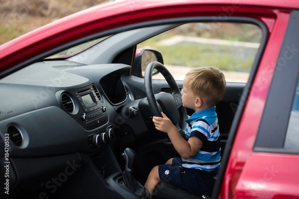 Fototapeta Cute little boy driving fathers car