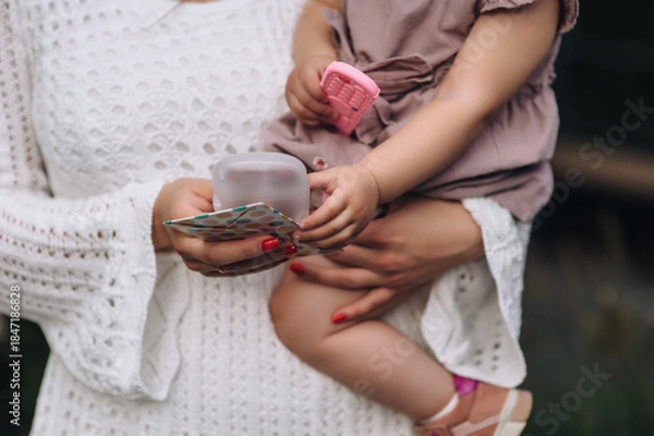 Obraz Photo of a young woman mother holding her child, her little daughter on her birthday with an envelope with money, gifts for the holiday.