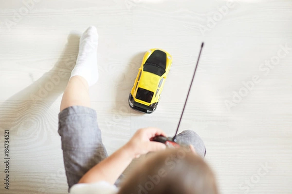 Obraz a boy playing with a car remote