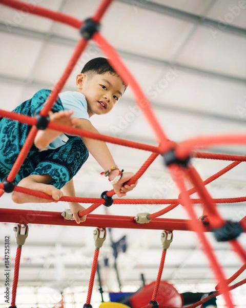 Fototapeta Asian Little Boy Climbing Rope Playground, Active Child Playing and Developing Skills