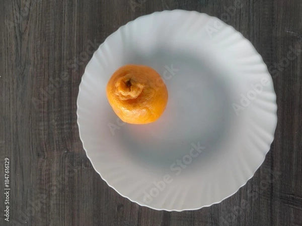 Fototapeta A fresh orange fruit on a white plate on table