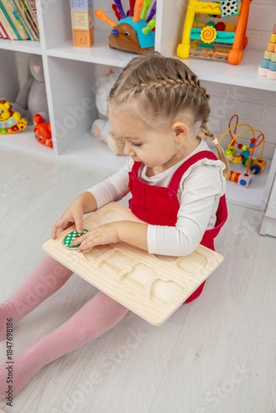 Obraz little girl playing with a wooden educational number puzzle toy