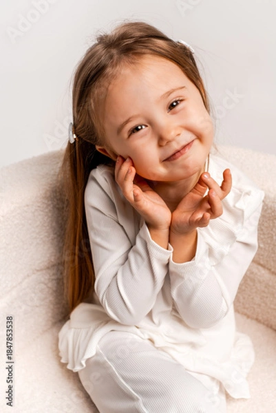 Fototapeta a girl child on a white cyclorama background, a girl in a white suit, a portrait, and space for text