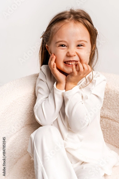 Fototapeta a girl child on a white cyclorama background, a girl in a white suit, a portrait, and space for text