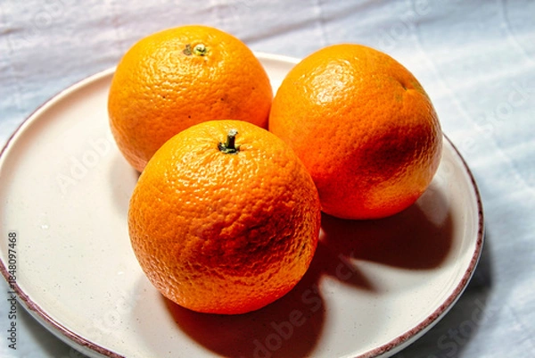 Obraz Three oranges are on a white plate