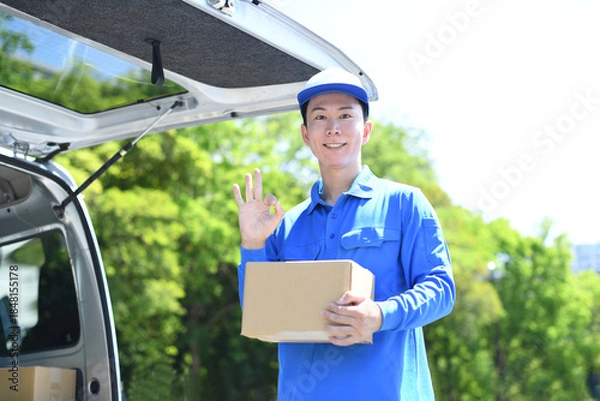 Obraz 屋外で配送スタッフが荷物を持ちOKをする