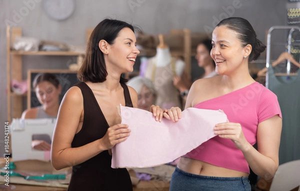 Obraz Two young women discussing sewn pattern during sewing master class