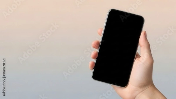 Obraz A hand holding a smartphone with empty screen against a soft gradient background for tech presentation