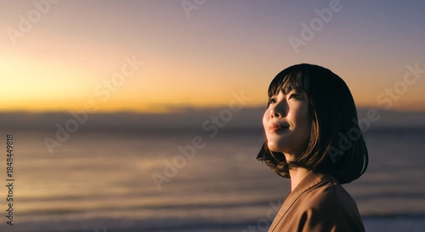 Obraz 美しい夕焼け・朝焼け　夕日・朝日に照らされた海と日の出の光を浴びた背景　笑顔で空を見上げ上を向きリラックスした表情の女性の横顔　日本・旅行・観光・アウトドア・リラクゼーションの背景　希望・安堵のイメージ　ビジネスはじまり・出勤・転職・就職