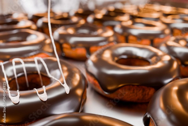 Obraz トレイに並んだドーナツに白い液体クリームを垂らす
