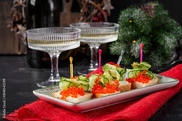 Fototapeta Christmas and New Year's dishes. Snacks and wine drinks for the holiday table. Canapes with red salmon caviar. Overhead