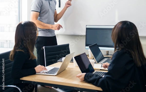 Fototapeta ホワイトボードで説明するオフィスのビジネスミーティング