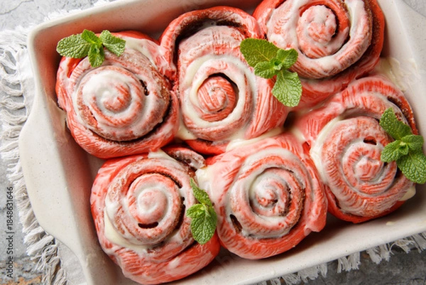 Obraz Festive pink cinnabon roll French buns with cinnamon and cream closeup on the plate on the table. horizontal top view from above