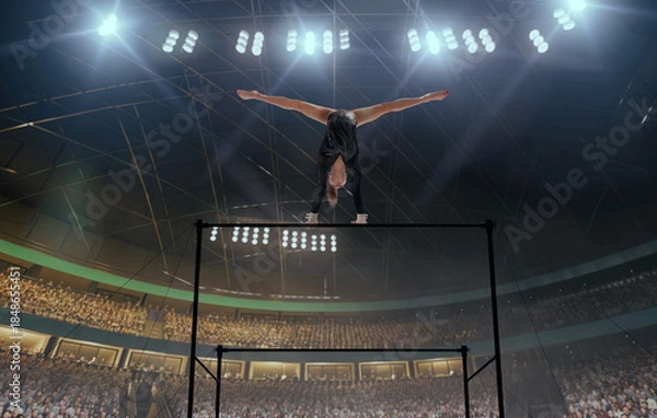 Fototapeta A gymnast performs a difficult trick on a horizontal bar.