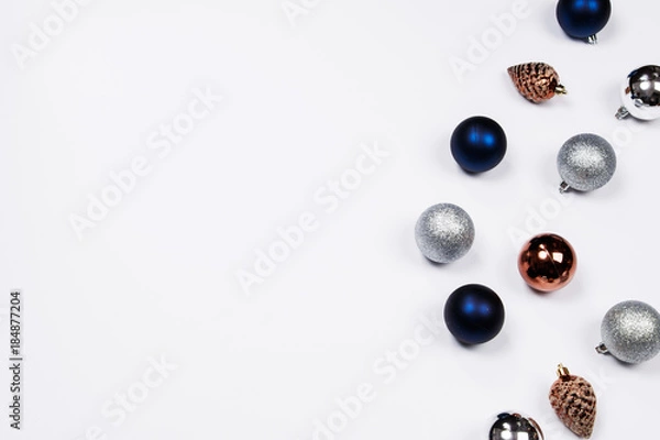 Fototapeta Christmas holiday background. Blue and silver glitter ball and gold pine cone christmas ornaments on a white background with copy-space. Top view.