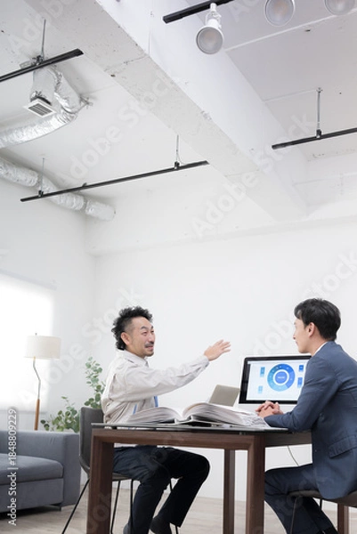 Fototapeta 作業着の男性とスーツの男性が内装工事や施工など打ち合わせをする