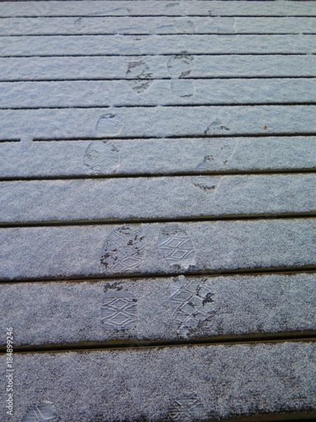 Fototapeta Foot prints in snow covered decking