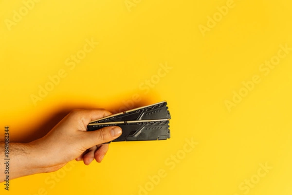 Obraz Hand presenting stack of desktop RAM modules on yellow background. High quality photo