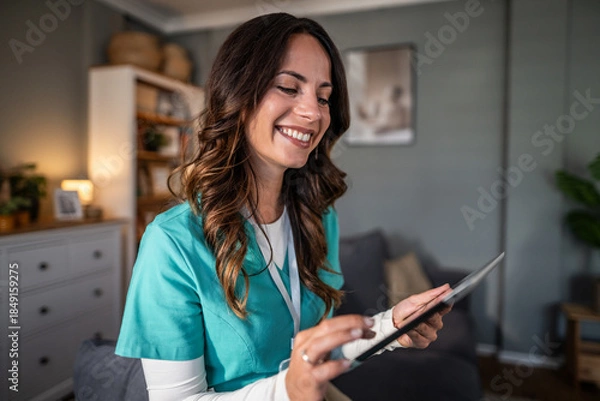 Obraz Smiling home care nurse using digital tablet
