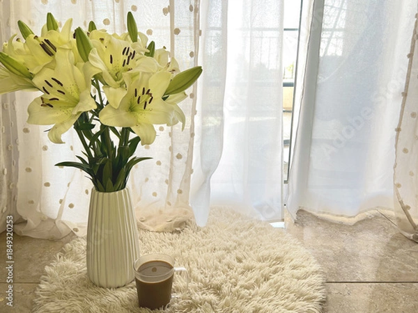 Fototapeta White Lilies in a Vase on beige carpet Near Sunlit Window. Morning cup of coffee.