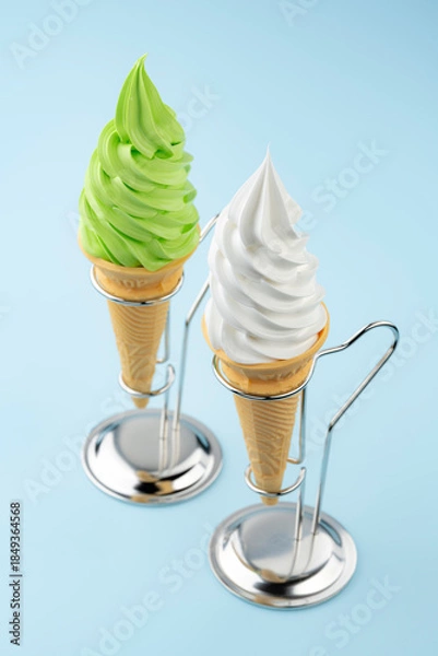 Obraz 水色背景に並ぶ抹茶ソフトクリームとバニラソフトクリームコーン二つと金属スタンド