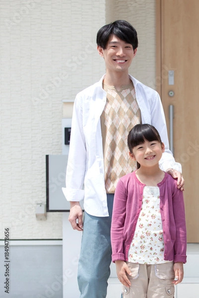 Obraz 玄関先に立つ父親と娘