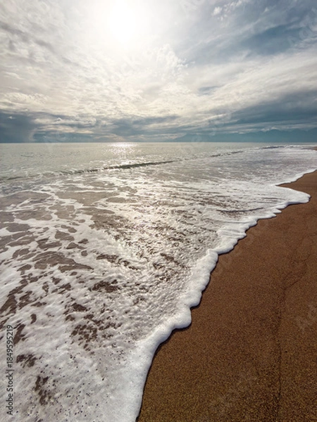 Obraz Gentle sea waves touching sandy beach under dramatic cloudy sky