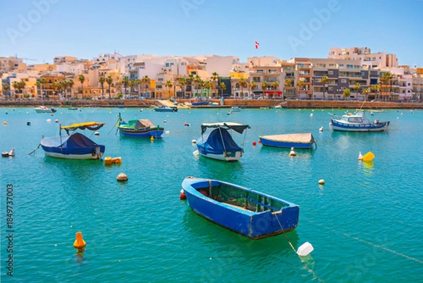 Obraz Marsaxlokk Harbour, Malta, is busy with colorful luzzu fishing boats in turquoise waters. Quaint waterfront buildings complete sunny Mediterranean scene
