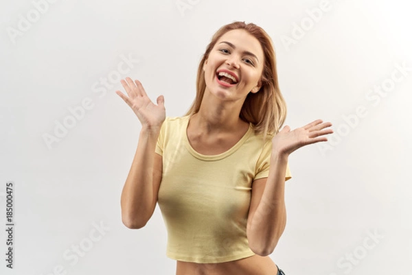 Fototapeta isolated high contrast Studio portrait of happy joyful young woman girl in yellow shirt with rapturous emotions and a distribution hand in hand and cheering.