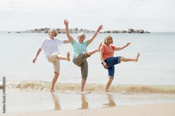 Obraz group of three senior mature retired women on their 60s having fun enjoying together happy walking on the beach smiling playful
