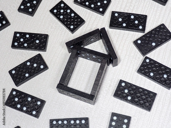 Fototapeta Dominoes arranged in the shape of a house. Rules and problems of buying or building a house. The process of designing a private house