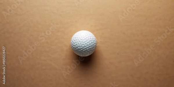 Fototapeta White golf ball on a cardboard background, highlighting sports equipment and gameplay focus, International Sports Day