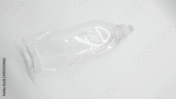 Obraz Clear plastic bottle lying on a white surface with reflections visible in light