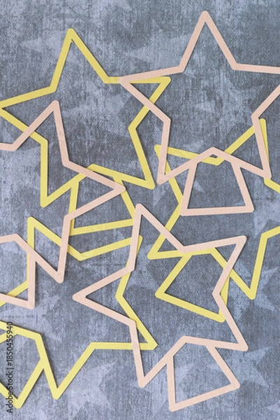 Obraz abstract star shape outlines machine-cut from pink and yellow paper and layered on paper with star pattern