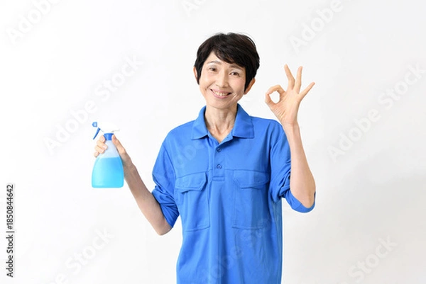 Obraz 清掃用スプレーを持ちOKサインをする作業服のアジア人の中高年女性