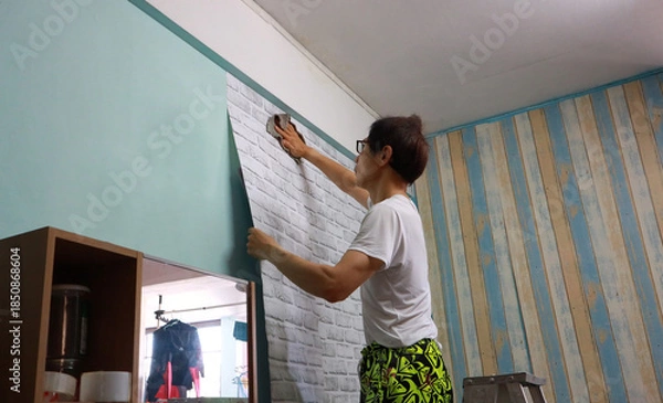 Obraz Man Decorating a Wall with DIY Home Renovation: Applying Brick Wallpaper
