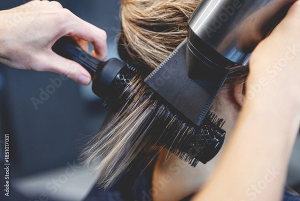 Obraz Hair of female client straightened with blow dryer and round brush, professional hairstylist styling