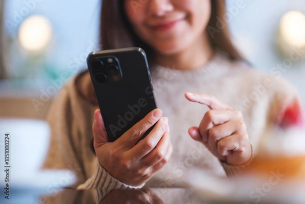 Obraz Closeup of a woman holding and using mobile phone in cafe