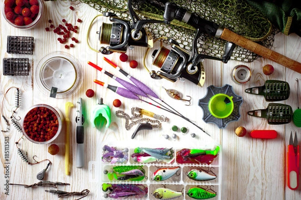 Obraz Fishing rods and spinnings in the composition with accessories for fishing on the old background on the table