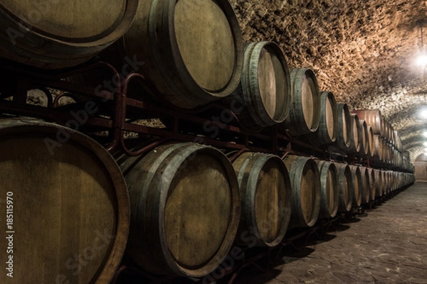 Fototapeta Wooden barrels of wine in the basement built of shellfish. Dark lighting