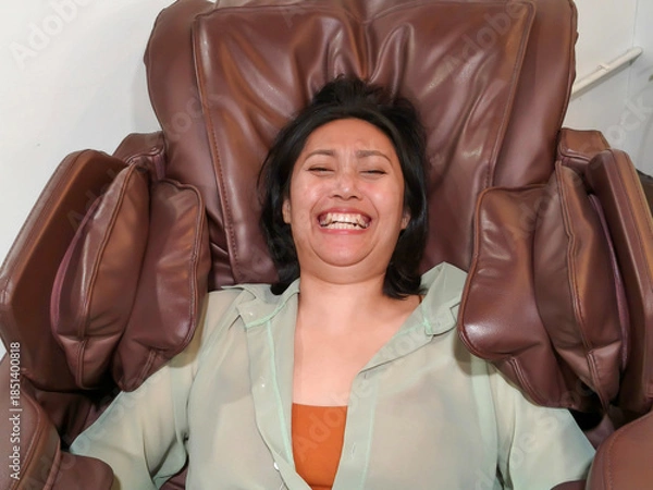 Obraz Closeup face of young asian woman is getting a leg massage with an electric massage chair to relieve aches and pains.