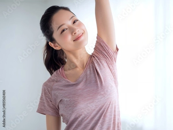 Obraz 明るい室内で腕を伸ばしてストレッチをしながら穏やかな笑顔を見せる女性の健康的な朝の習慣