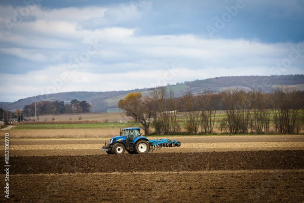 Obraz Tractor plowing a hilly rural field