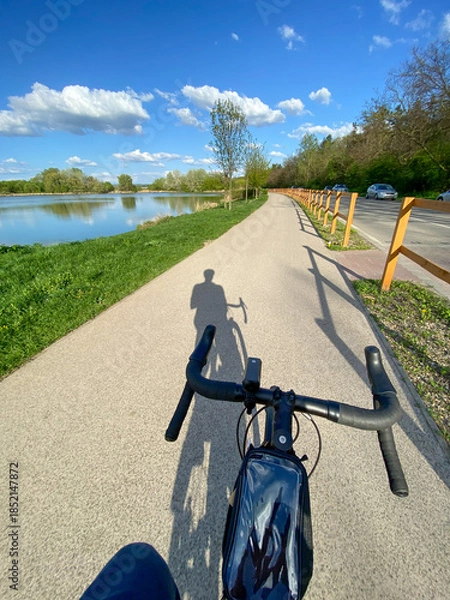 Obraz cyclist shadow on lakeside bike path