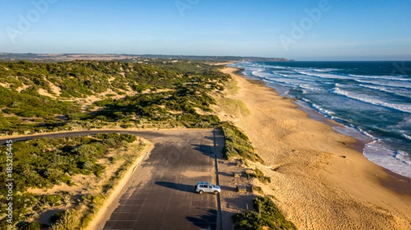 Fototapeta Australian Beach at Sunrise with a person in a car enjoying the view. The long beach is located in Saint Andrews Australia.