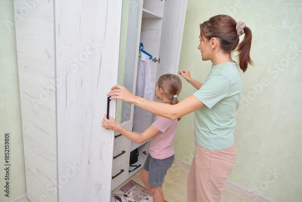 Obraz Mother and daughter sorting clothes in a cozy room.