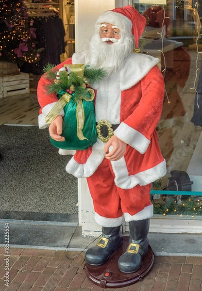 Obraz life-size moving Santa Claus statue stands outside a shop entrance